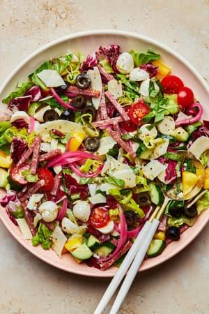Italian Chopped Salad with homemade Italian salad dressing in a serving bowl with serving spoons on the counter