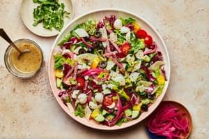 Italian Chopped Salad with homemade Italian salad dressing in a serving bowl with serving spoons on the counter