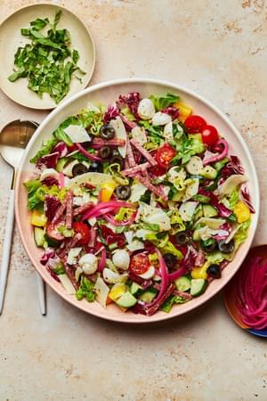 Italian Chopped Salad with homemade Italian salad dressing in a serving bowl with serving spoons on the counter