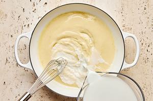 milk being whisked into a skillet with butter and flour