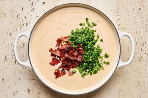 mixing cooked chopped bacon and minced jalapeños into cheese sauce in a skillet