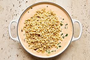 cooked macaroni noodles being stirred into jalapeño popper cheese sauce made with cream cheese, cheddar and pepper jack