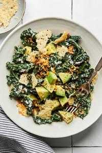 kale caesar salad made with homemade caesar dressing, avocado, toasted panko breadcrumbs and parmesan in a bowl with a fork