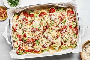 lasagna stuffed zucchini boats in a baking dish sprinkled with Parm, parsley and red pepper flakes