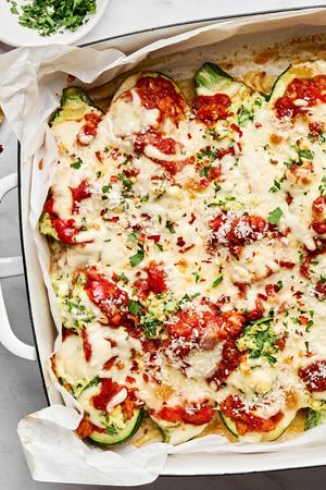 lasagna stuffed zucchini boats in a baking dish sprinkled with Parmesan, parsley and red pepper flakes