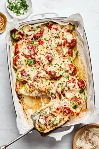 lasagna stuffed zucchini boats in a baking dish sprinkled with Parmesan, parsley and red pepper flakes
