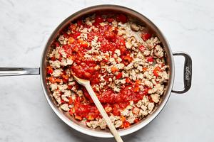 ground chicken, bell pepper, and garlic being cooked in olive oil in a skillet