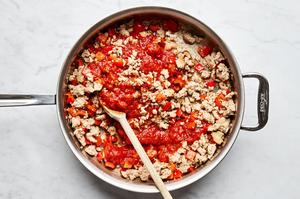 ground chicken, bell pepper, and garlic being cooked in olive oil in a skillet
