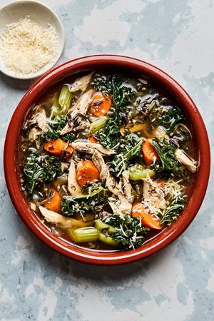 a bowl of Leftover Turkey Soup with Wild Rice made with carrots, celery, onion, garlic, spices and kale topped with Parmesan