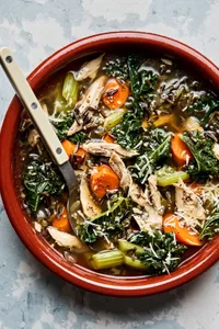 a bowl of Leftover Turkey Soup with Wild Rice made  with carrots, celery, onion, garlic, spices and kale topped with Parmesan