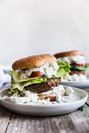two Mediterranean Turkey Burgers With Tzatziki tomatoes on plates