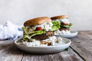 two Mediterranean Turkey Burgers With Tzatziki tomatoes on plates