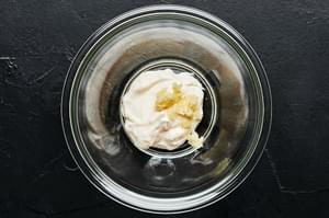 mayonnaise and garlic in a small glass bowl to be combined for garlic mayo