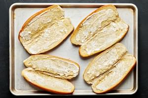 open hoagie rolls with butter spread on one half and garlic mayo spread on the other half