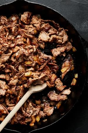 cooked steak in a cast iron skillet to be used for Philly cheesesteak sandwiches