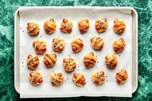 homemade pigs in a blanket seasoned with coarse salt and everything but the bagel seasoning on a parchment lined baking sheet