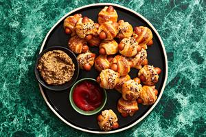 pigs in a blanket topped with everything bagel seasoning on a serving platter served with ground mustard and ketchup