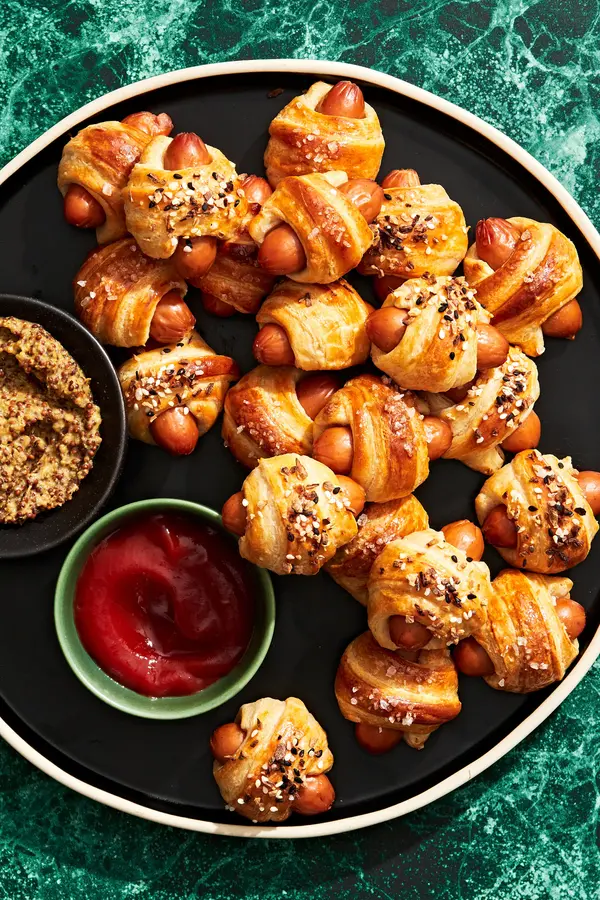 pigs in a blanket topped with everything bagel seasoning on a serving platter served with ground mustard and ketchup