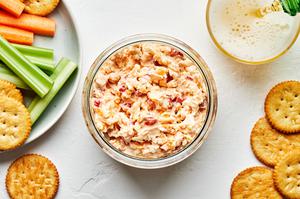 homemade pimento cheese in a bowl surrounded by ritz cracker, celery and carrots for dipping