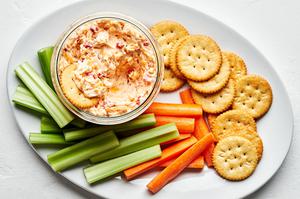 homemade pimento cheese in a bowl on a serving platter with celery, carrots and ritz crackers