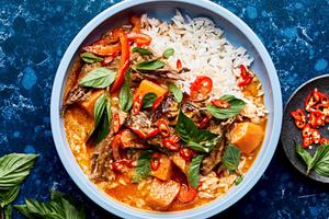 red curry beef with sweet potatoes, onion and red bell peppers served over rice topped with cilantro and basil