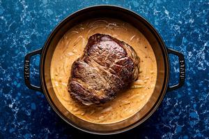 a seared chuck roast in a red curry sauce cooking in a soup pot