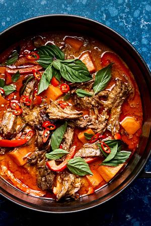 a pot of red curry beef made with sweet potatoes, onion, red bell peppers, coconut milk, lemon grass, lime juice and ginger