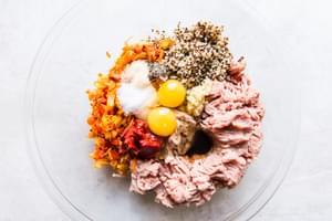 ground turkey, 2 raw eggs, cooked quinoa, spices and sautéed veggies in a bowl .