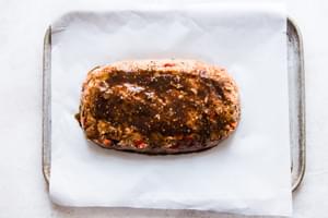 raw meatloaf on a baking sheet with a brown sugar Worcestershire glaze on it