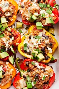 stuffed peppers filled with ground turkey, quinoa, black beans, and tomatoes topped with pepper jack cheese, avocado