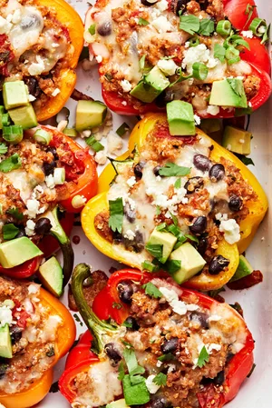 stuffed peppers filled with ground turkey, quinoa, black beans, and tomatoes topped with pepper jack cheese, avocado