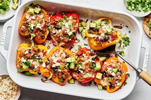baking dish filled with ground turkey stuffed peppers topped with melted cheese, avocado, cilantro being served with a spoon