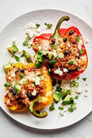 2 ground turkey stuffed peppers on a plate topped with cheese and avocado
