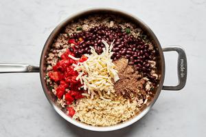 browned ground turkey in a skillet with cooked quinoa, canned tomatoes, taco seasoning, black beans and pepper jack cheese.
