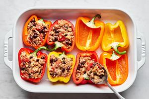 bell pepper halves in a baking dish being filled with ground turkey, cheese, beans and quinoa
