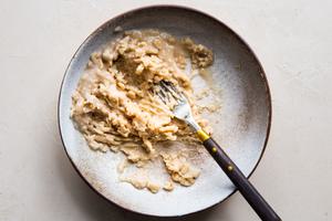 white beans smashed in a small bowl with a fork