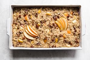 Baked oatmeal with apples and pecans and maple syrup in a baking dish