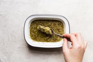 hand whisking dried herbs, melted butter and garlic in a small dish with a fork