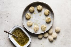 frozen dinner rolls in a herb and garlic melted butter and placing them in a pan.