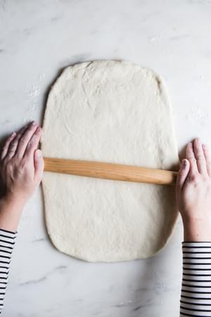 hands rolling out dough for dairy free cinnamon rolls