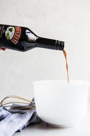 bailey's irish cream liquor being poured into a mixing bowl