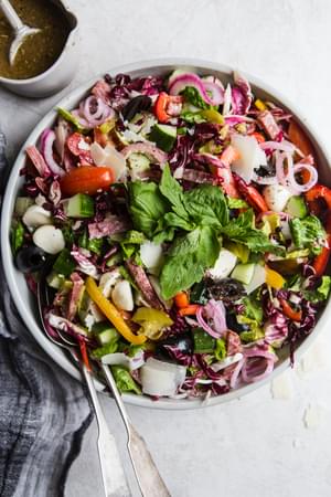 Italian chop salad in a bowl with onions, olives, salami and tomatoes