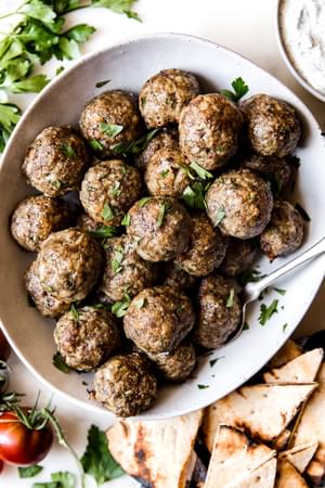 mediterranean beef meatballs in a bowl with tzatziki sauce