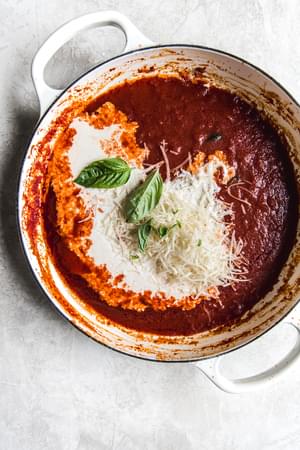 tomato cream sauce in a pan with basil and parmesan cheese