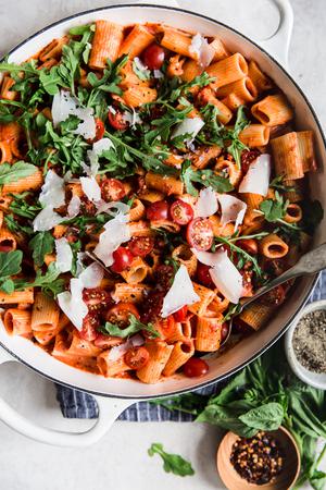 pasta dish with tomato cream sauce arugula and parmesan