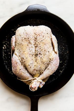 whole raw chicken in a cast iron skillet seasoned with salt and pepper