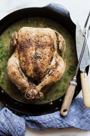 whole roast chicken in a skillet with a carving knife