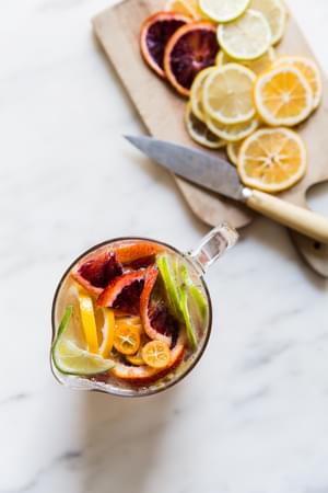 citrus fruit chopped into a pitcher on a marble surface