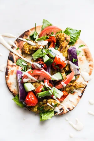 chicken shawarma on a pita drizzled with tahini sauce