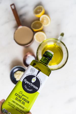 hand pouring extra virgin olive oil being poured out of a bottle into a measuring cup
